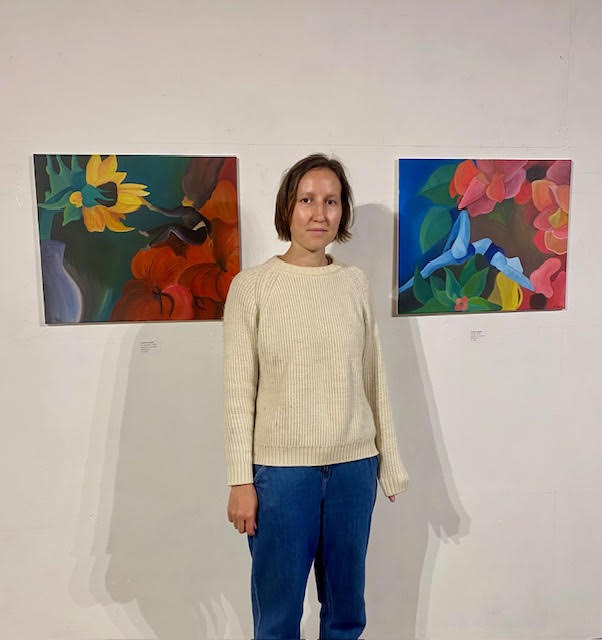 Artist Isy Malik with two of her paintings in her solo exhibition at Redwing Gallery.